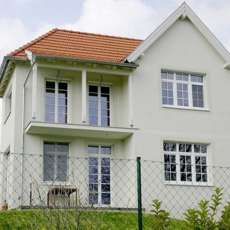 Helles Haus mit orangenen Dach und hohen Fenstern